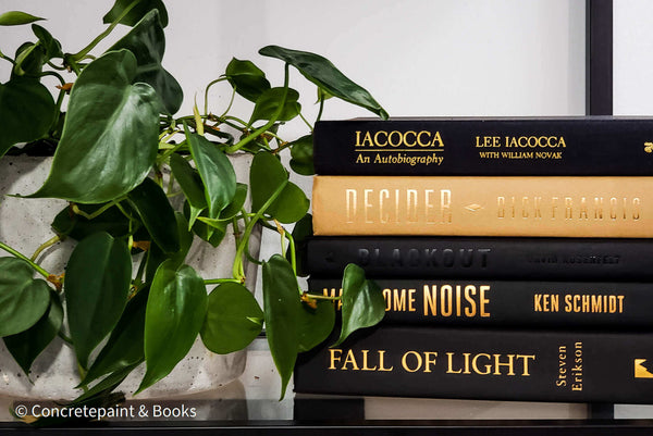 modern Book display stack and concrete planter used as decor on shelf. Stack of hardcover books decorating bedroom. 