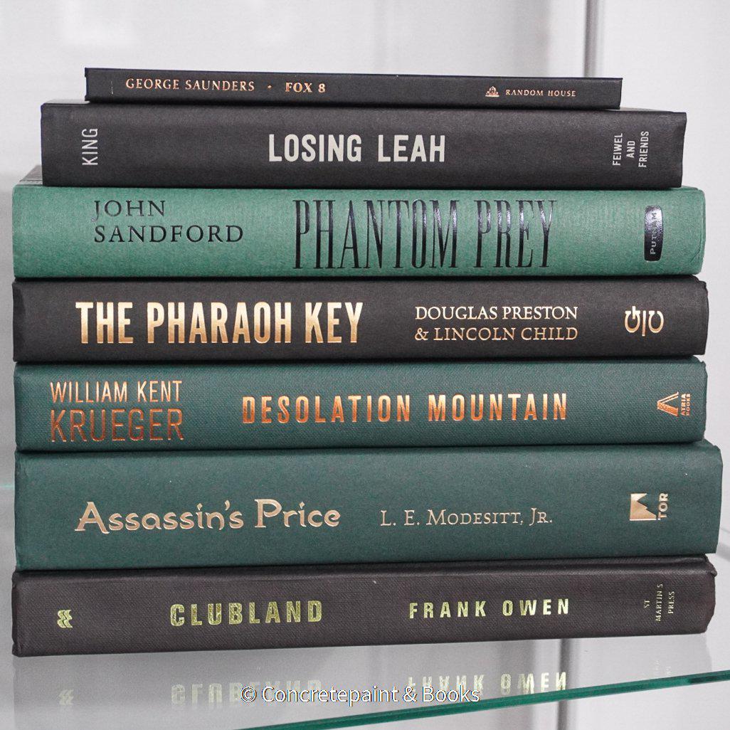 Black and green hardcover real books staged and used as home décor. Book stack on a shelf.