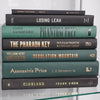 Black and green hardcover real books staged and used as home décor. Book stack on a shelf.