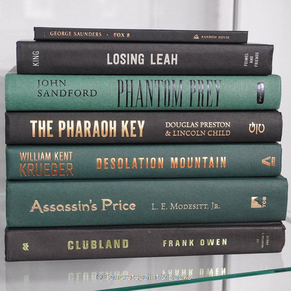Black and green hardcover real books staged and used as home décor. Book stack on a shelf.