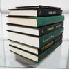Black and green hardcover real books staged and used as home décor. Book stack on a shelf.