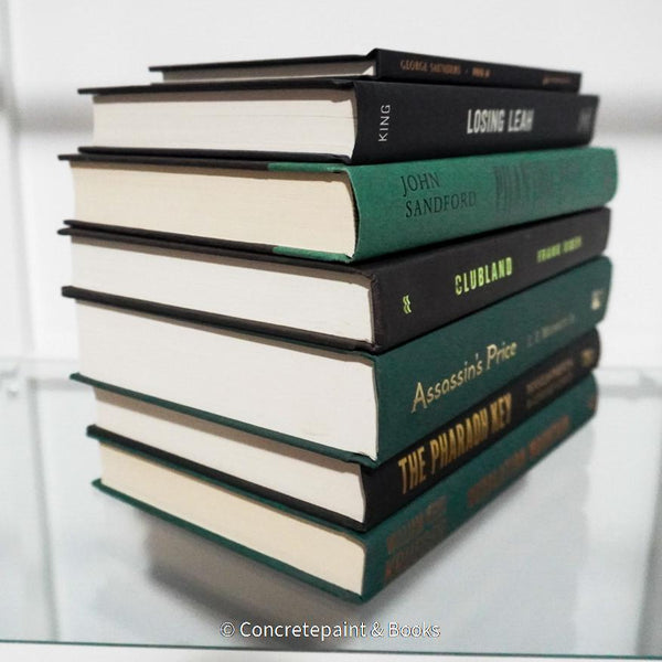 Black and green hardcover real books staged and used as home décor. Book stack on a shelf.