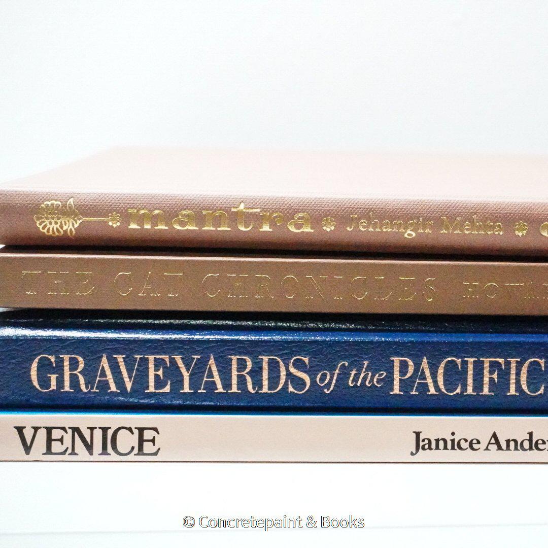 Stack of hardcover books in navy blue and neutral colors. Real books staged and used for decorating.