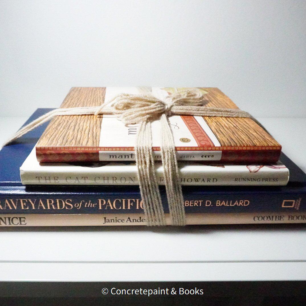 Stack of hardcover books in navy blue and neutral colors. Real books staged and used for decorating.