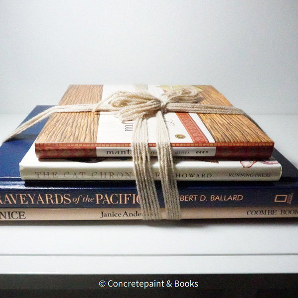 Stack of hardcover books in navy blue and neutral colors. Real books staged and used for decorating.