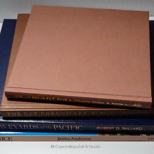 Stack of hardcover books in navy blue and neutral colors. Real books staged and used for decorating.