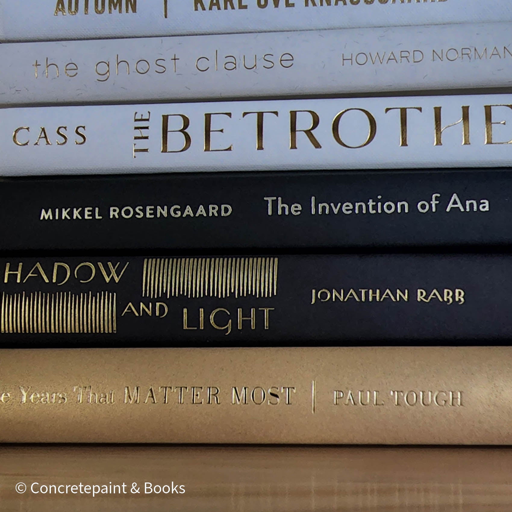 Stack of gold, black, and white book display. Real books used for modern and glam decorating. 