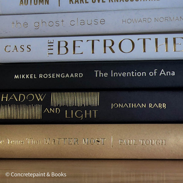 Stack of gold, black, and white book display. Real books used for modern and glam decorating. 