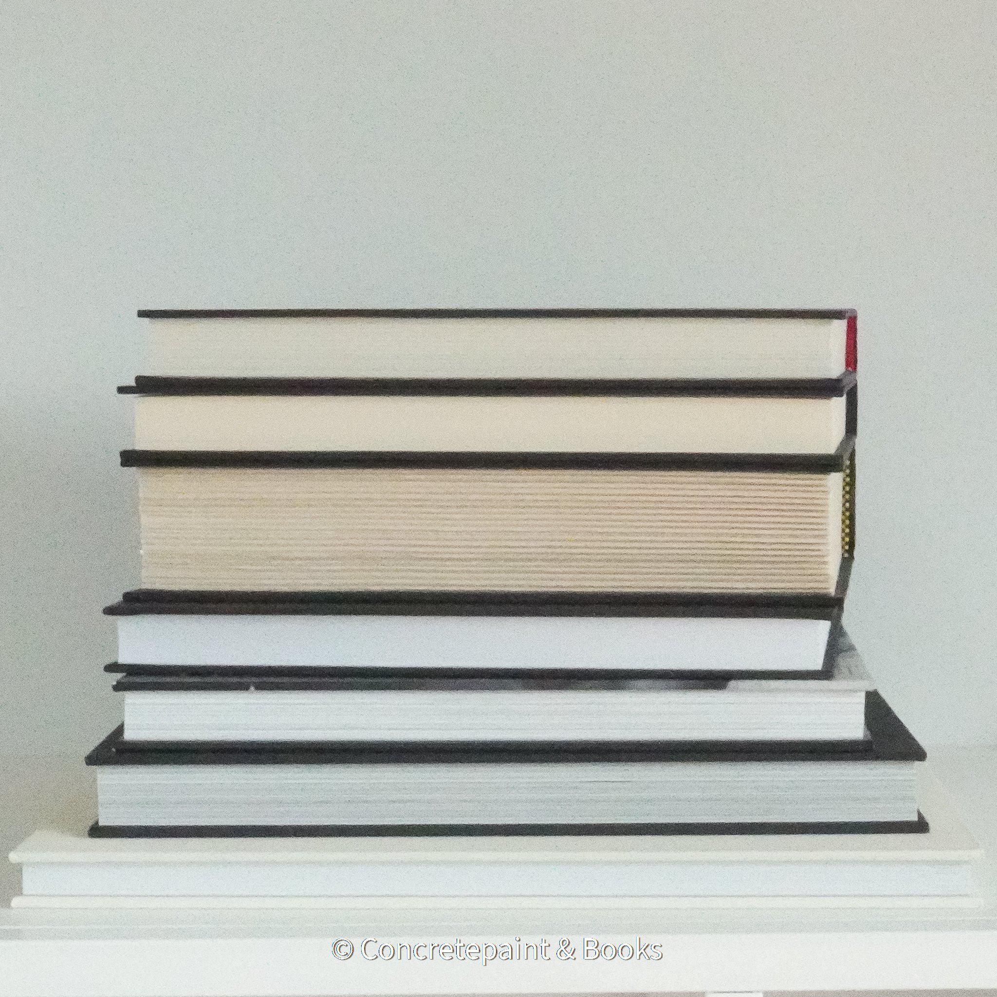 Real books used as home décor. Stack of all black hardcover books including coffee table books, and novels.