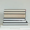 Real books used as home décor. Stack of all black hardcover books including coffee table books, and novels.