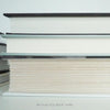 Real books used as home décor. Stack of all black hardcover books including coffee table books, and novels.