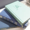 Neutral, mint, and navy color books used for decorating. Stack of real hardcover books for display. 