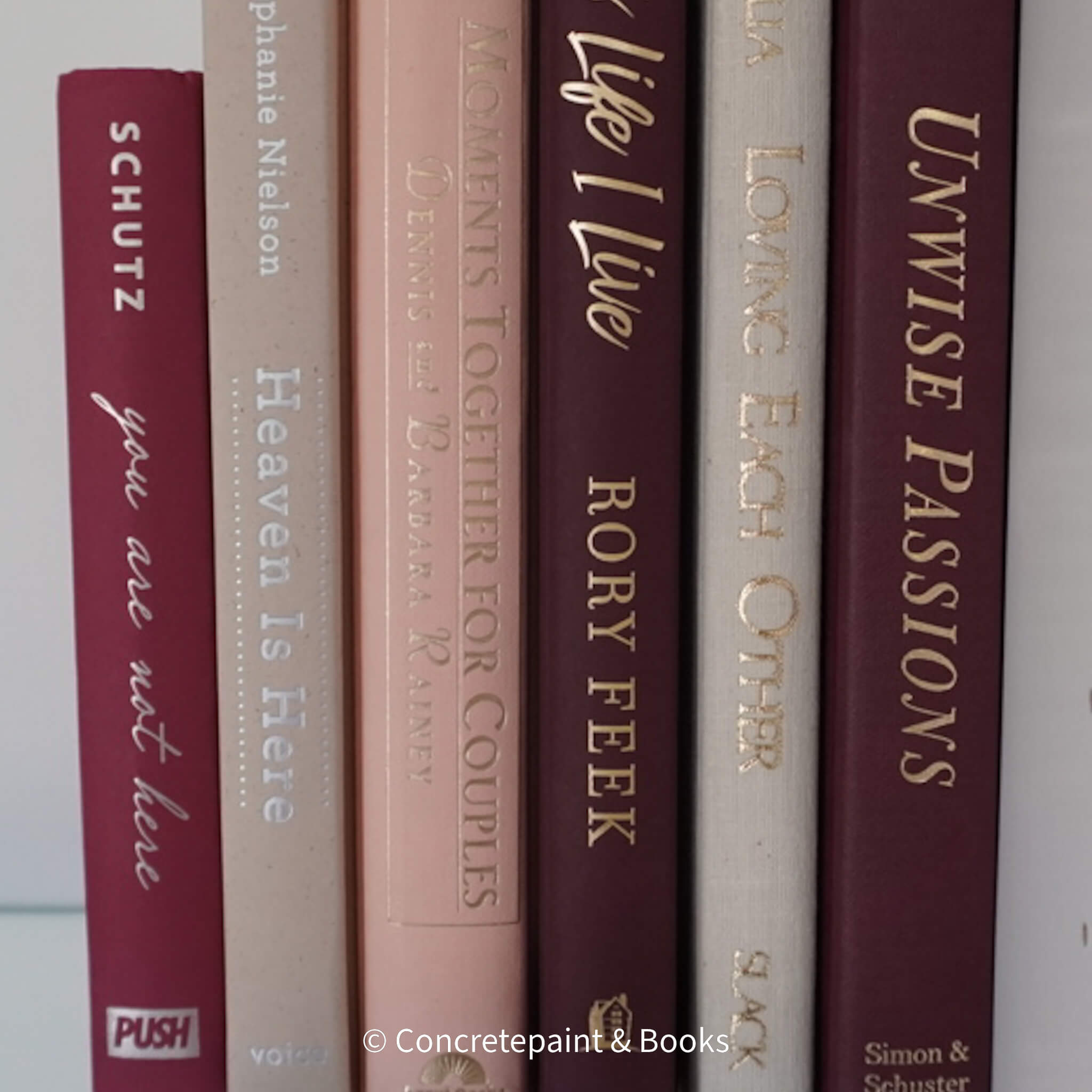 Stack of burgundy, blush, and neutral color books. Real hardcover books used for decorating.