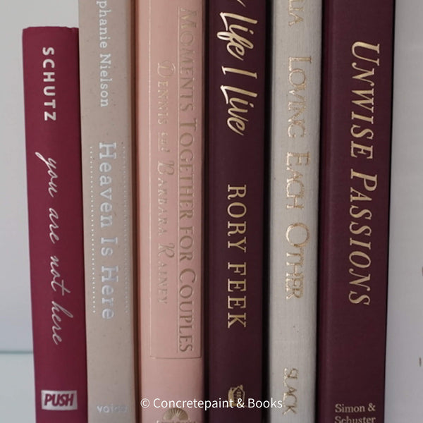 Stack of burgundy, blush, and neutral color books. Real hardcover books used for decorating.