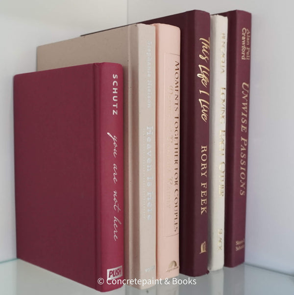 Stack of burgundy, blush, and neutral color books. Real hardcover books used for decorating.