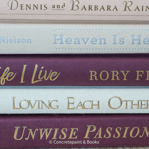 Stack of burgundy, blush, and neutral color books. Real hardcover books used for decorating.