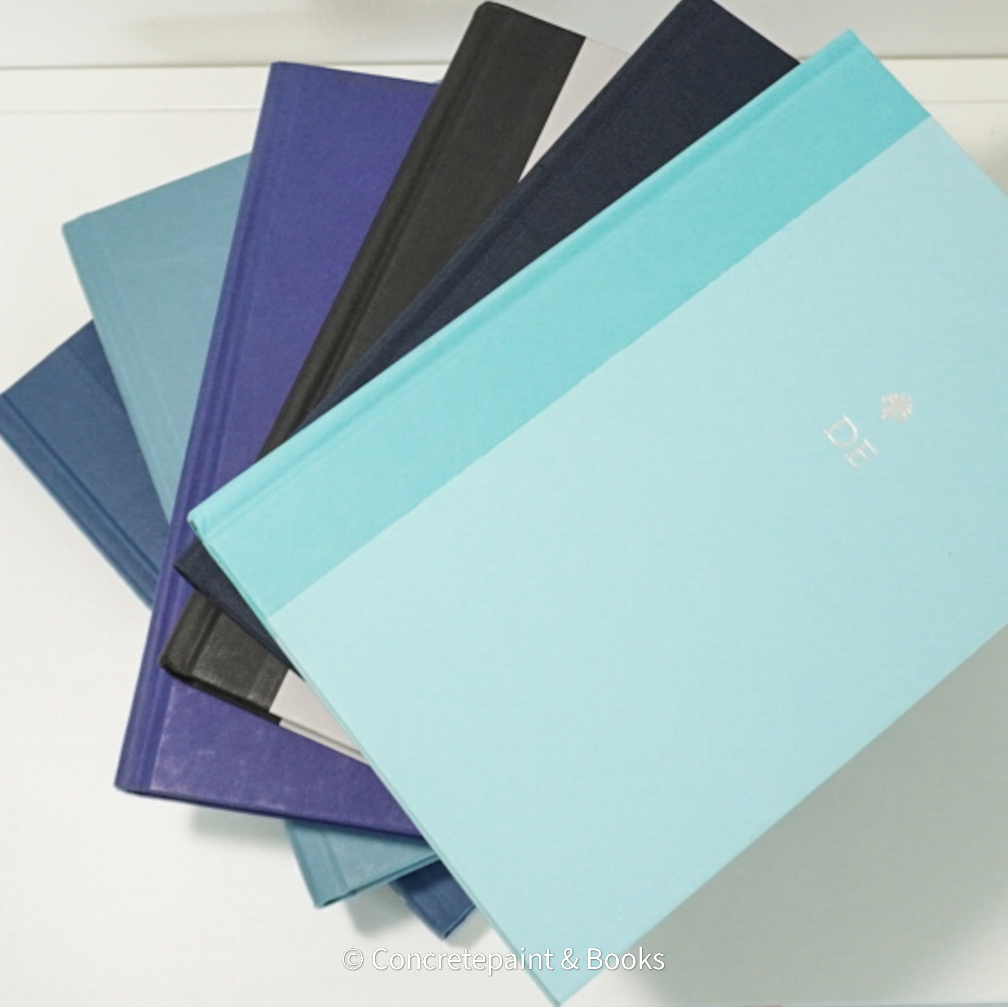 Stack of blue and black hardcover book on IKEA shelf.