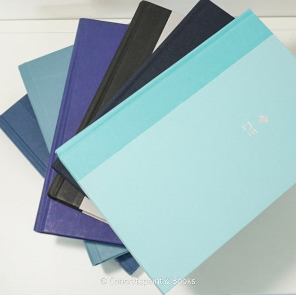 Stack of blue and black hardcover book on IKEA shelf.