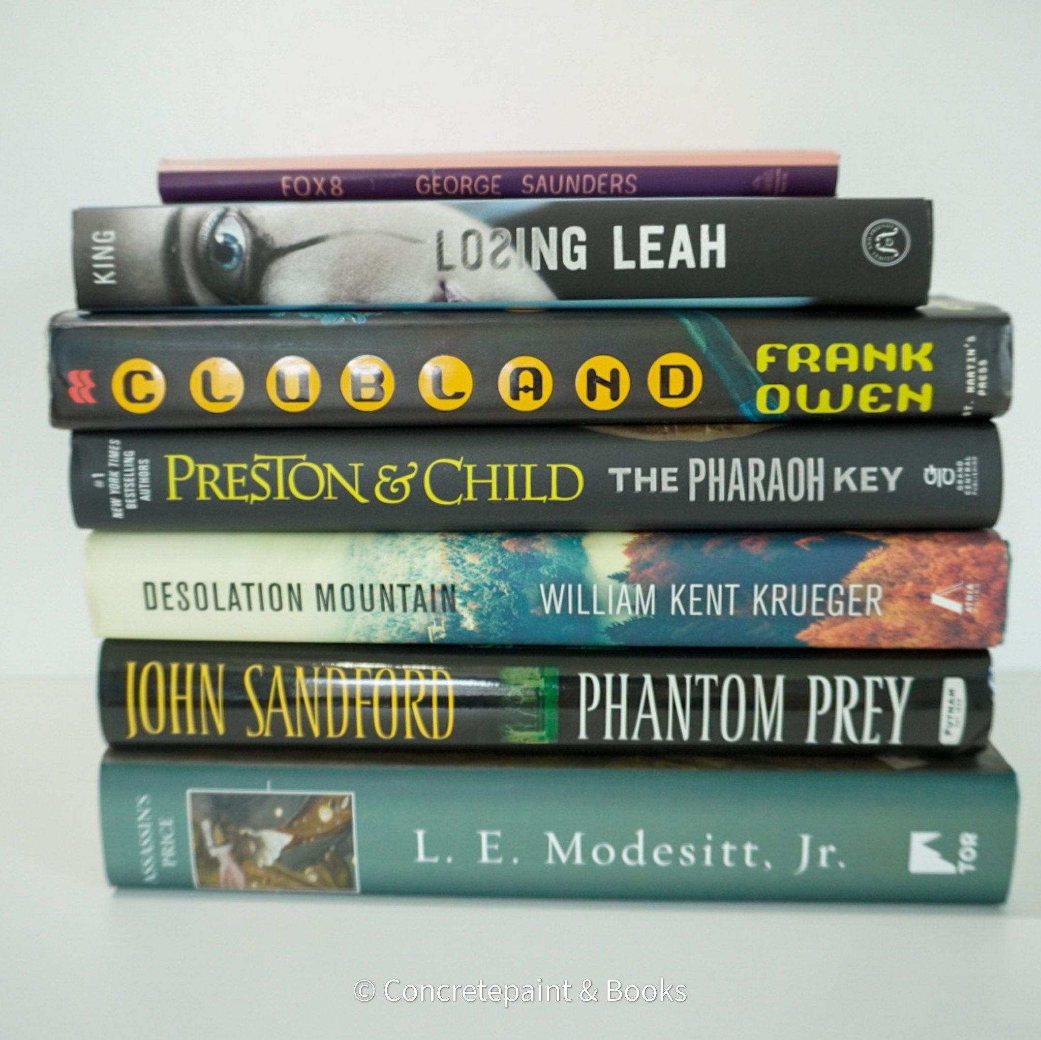 Black and green hardcover real books staged and used as home décor. Book stack on a shelf.