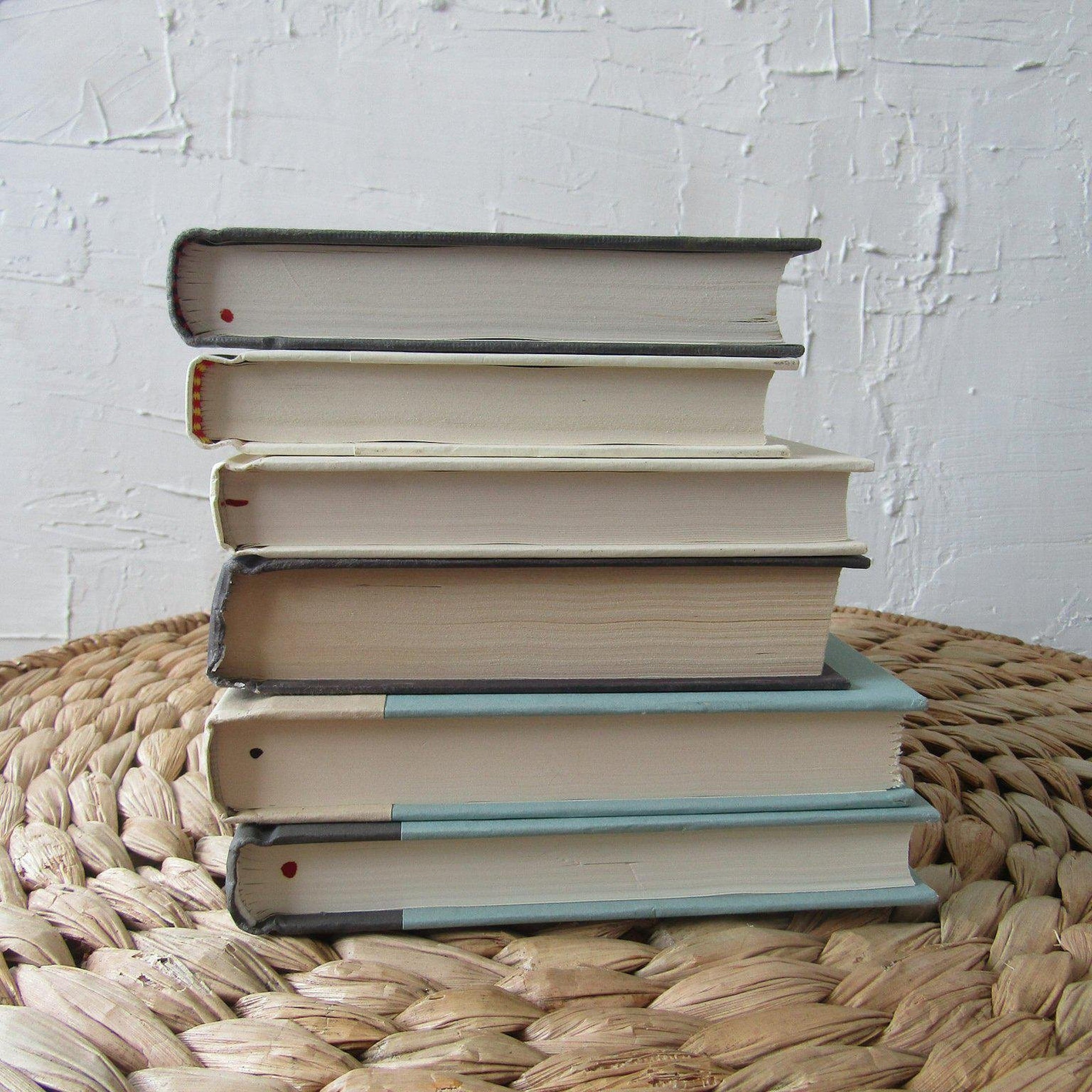 Set of hardcover books in gray and neutral colors staged and used as decorating home display. 