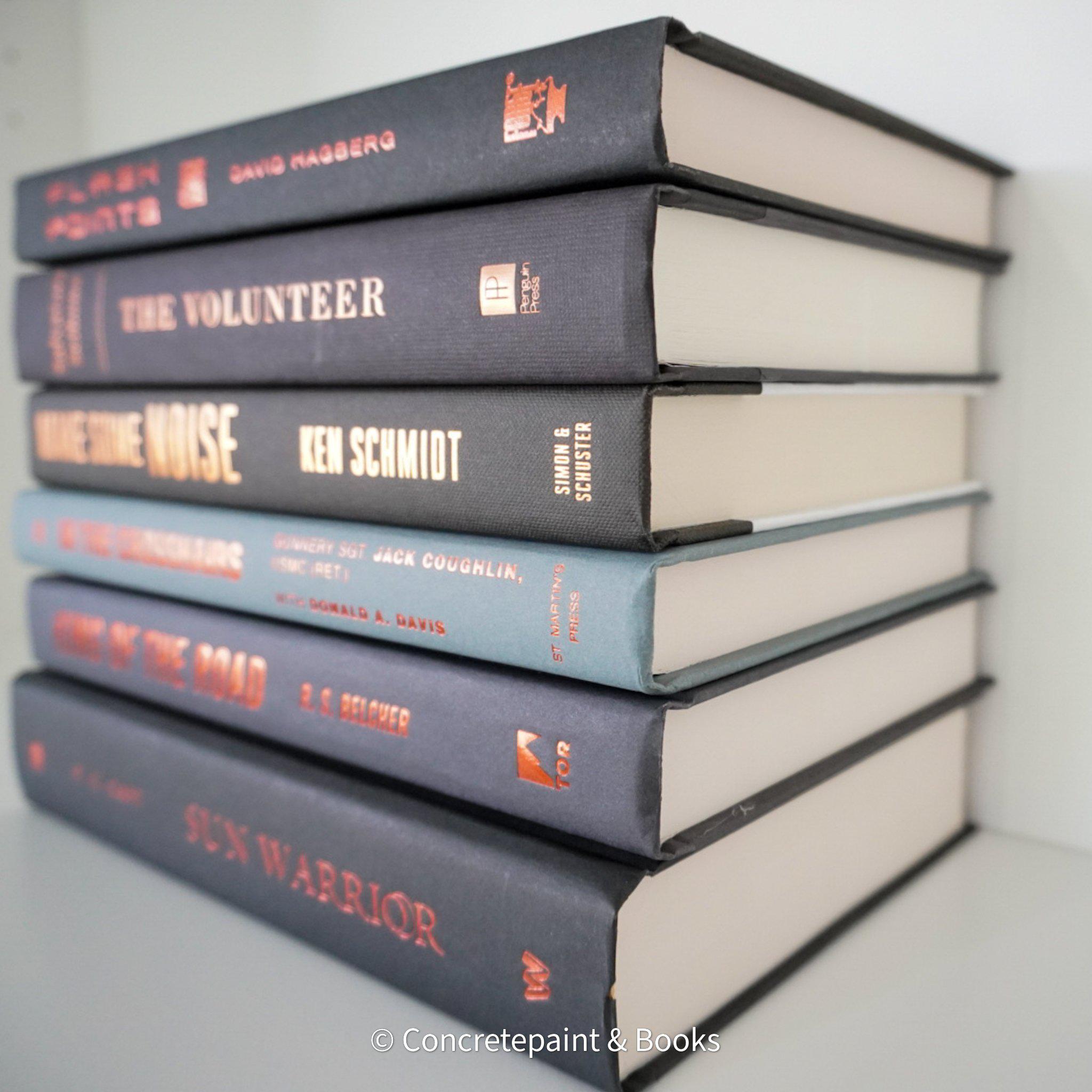 Stack of black and gray hardcover books with copper font. Real books staged and used as shelf décor.