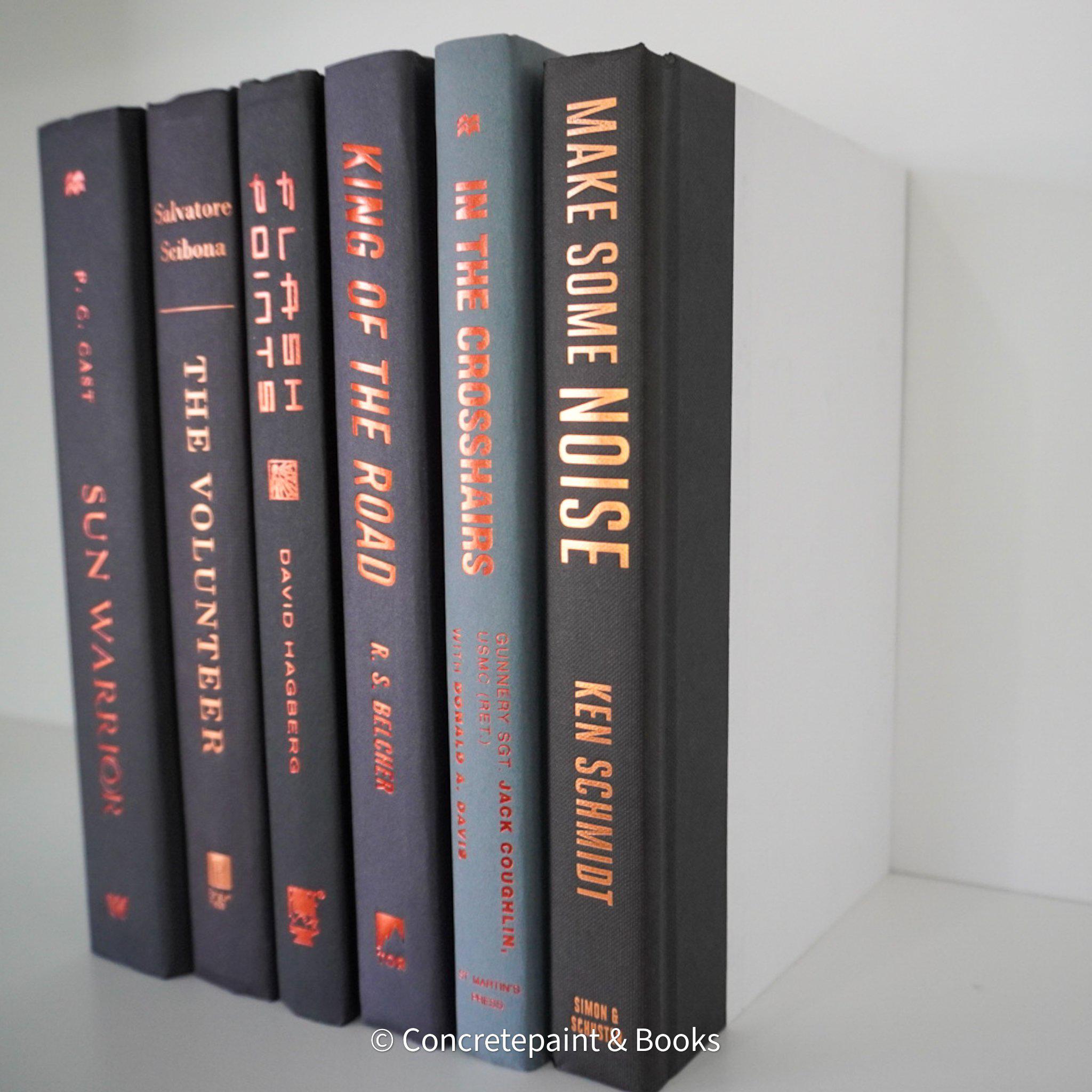 Stack of black and gray hardcover books with copper font. Real books staged and used as shelf décor.