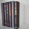 Stack of black and gray hardcover books with copper font. Real books staged and used as shelf décor.