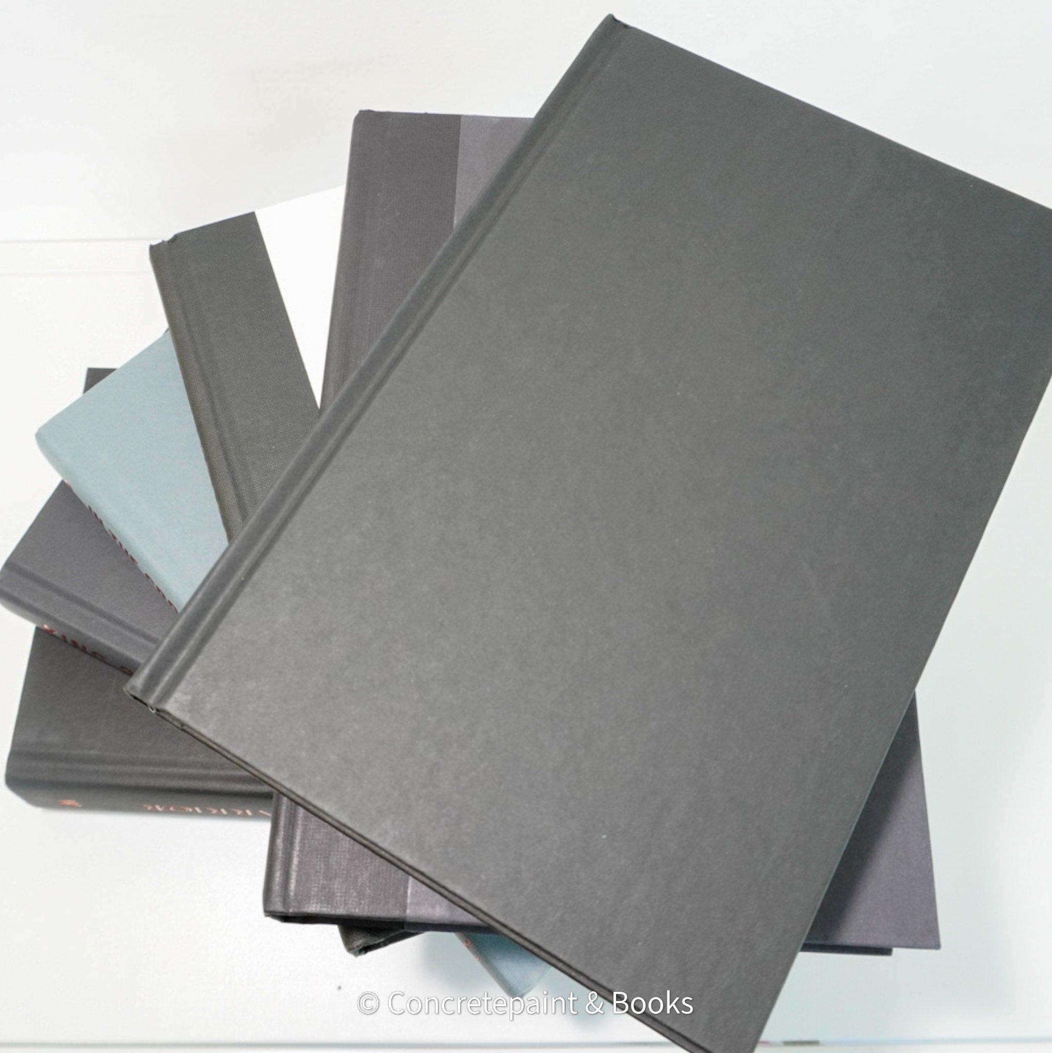 Stack of black and gray hardcover books with copper font. Real books staged and used as shelf décor.