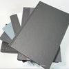 Stack of black and gray hardcover books with copper font. Real books staged and used as shelf décor.