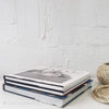 Real headcover books used as staged home décor. Stack of large black coffee table books with ikea seagrass basket on top.