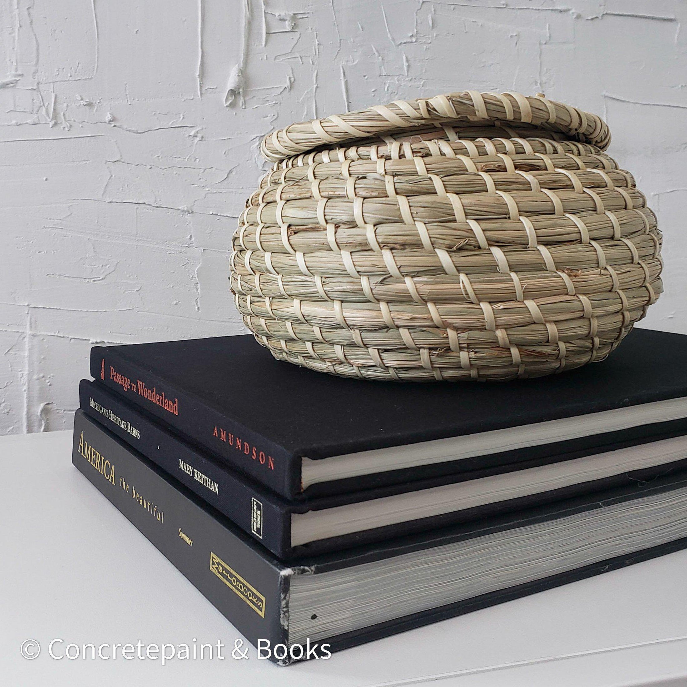 Real headcover books used as staged home décor. Stack of large black oblong coffee table books with ikea seagrass basket. Mens bachelor pad decor for sale.