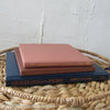 Stack of hardcover books in navy blue and neutral colors. Real books staged and used for decorating.