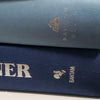 stack of real hardcover books used as shelf décor in blues, white, and gray.