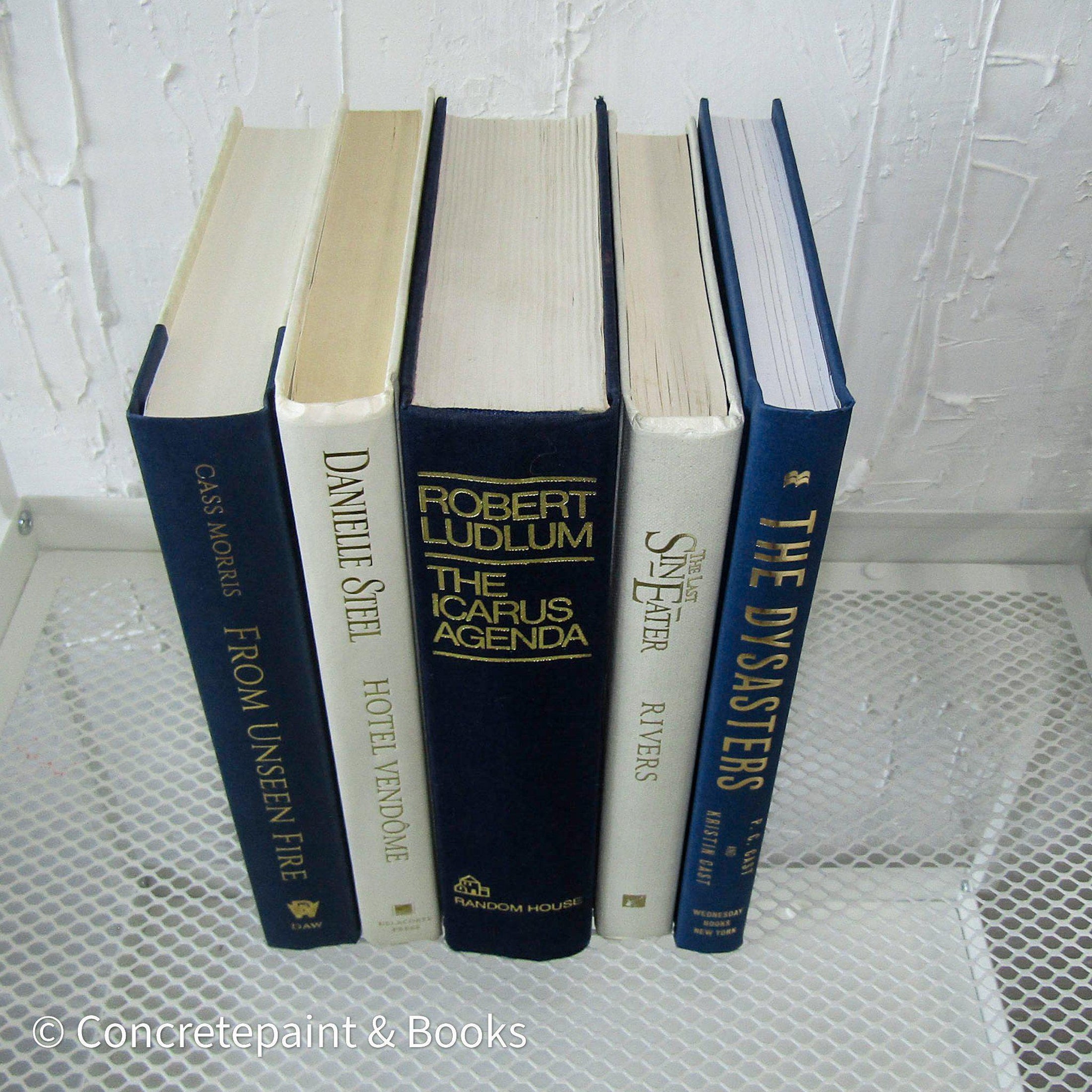 stack of real hardcover books in navy blue and neutral colors. 