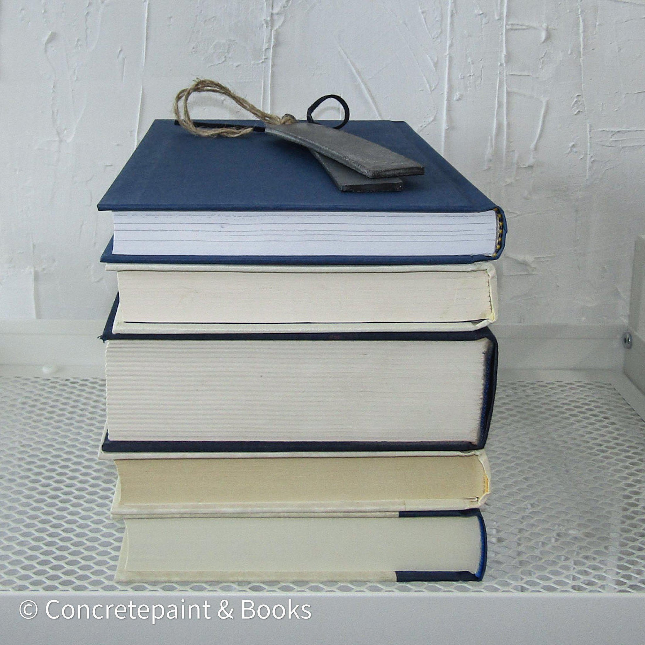 Stack of real hardcover books in navy blue and neutral colors. 