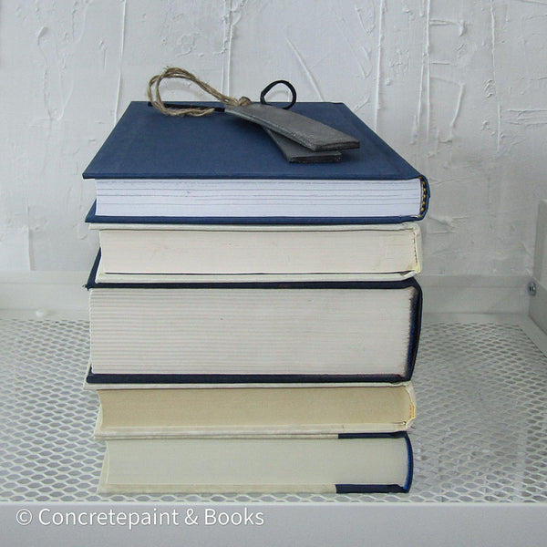 Stack of real hardcover books in navy blue and neutral colors. 