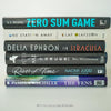 Black and blue hardcover real books staged and used as home décor. Book stack on a shelf.