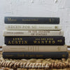 Set of hardcover books in gray and neutral colors staged and used as decorating home display. 
