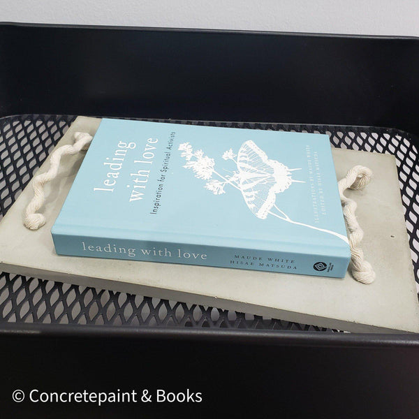Decorative concrete tray with light blue hardcover book on top. Leading with Love Book and concrete home décor.