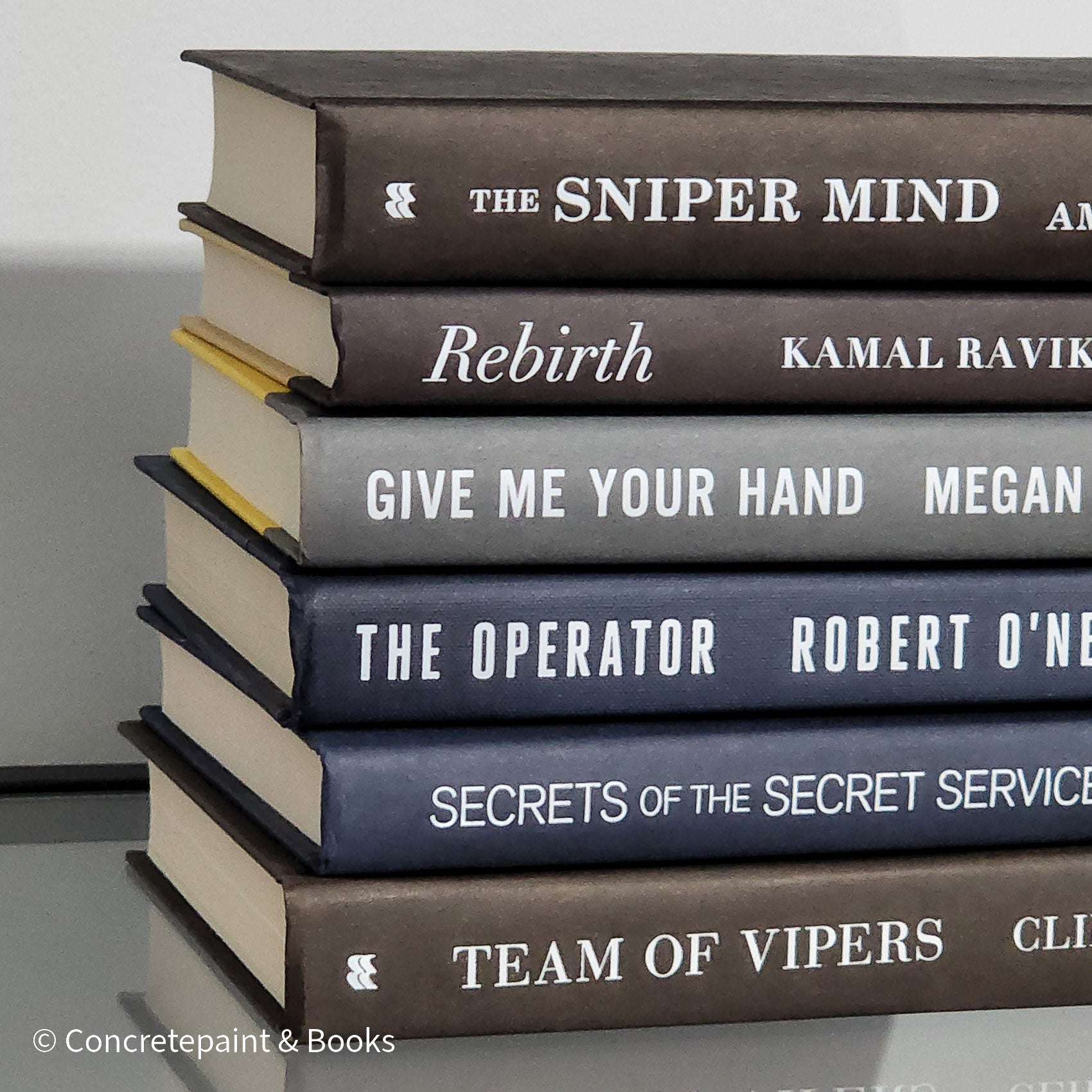 Stack of black blue and Gray books used as men's shelf decor.