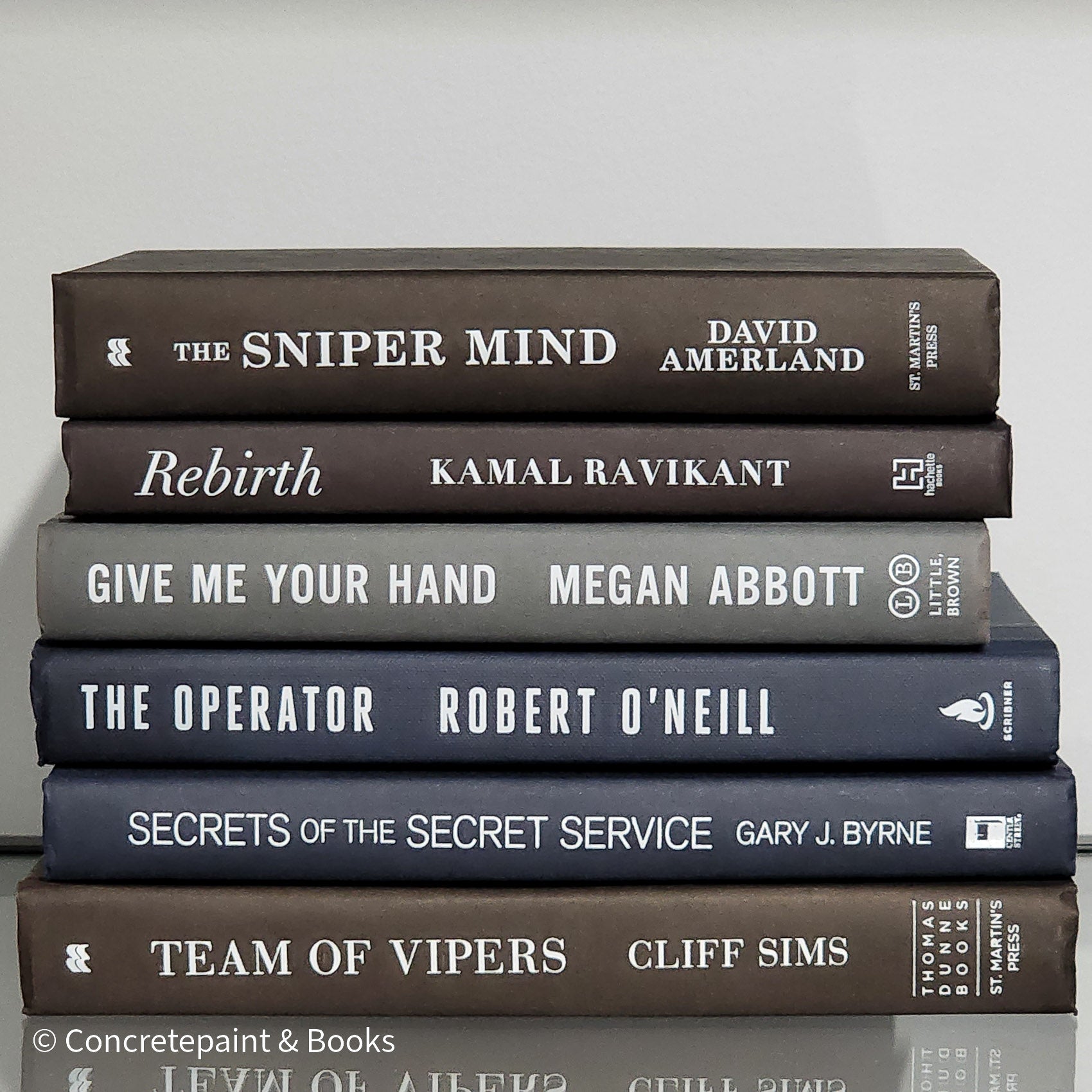 Stack of black blue and Gray books used as men's shelf decor.