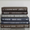 Stack of black blue and Gray books used as men's shelf decor.