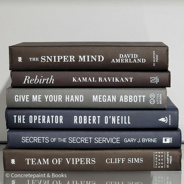 Stack of black blue and Gray books used as men's shelf decor.
