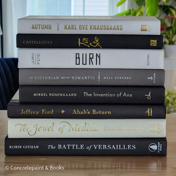 Black gray white and neutral books on display. Stack of decorative books.