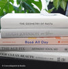 Set of decorative books for display. Real hardcover books in white, blush, and silver purple used for decorating. Decorative cookbook, cocktail book, and coffee table book.