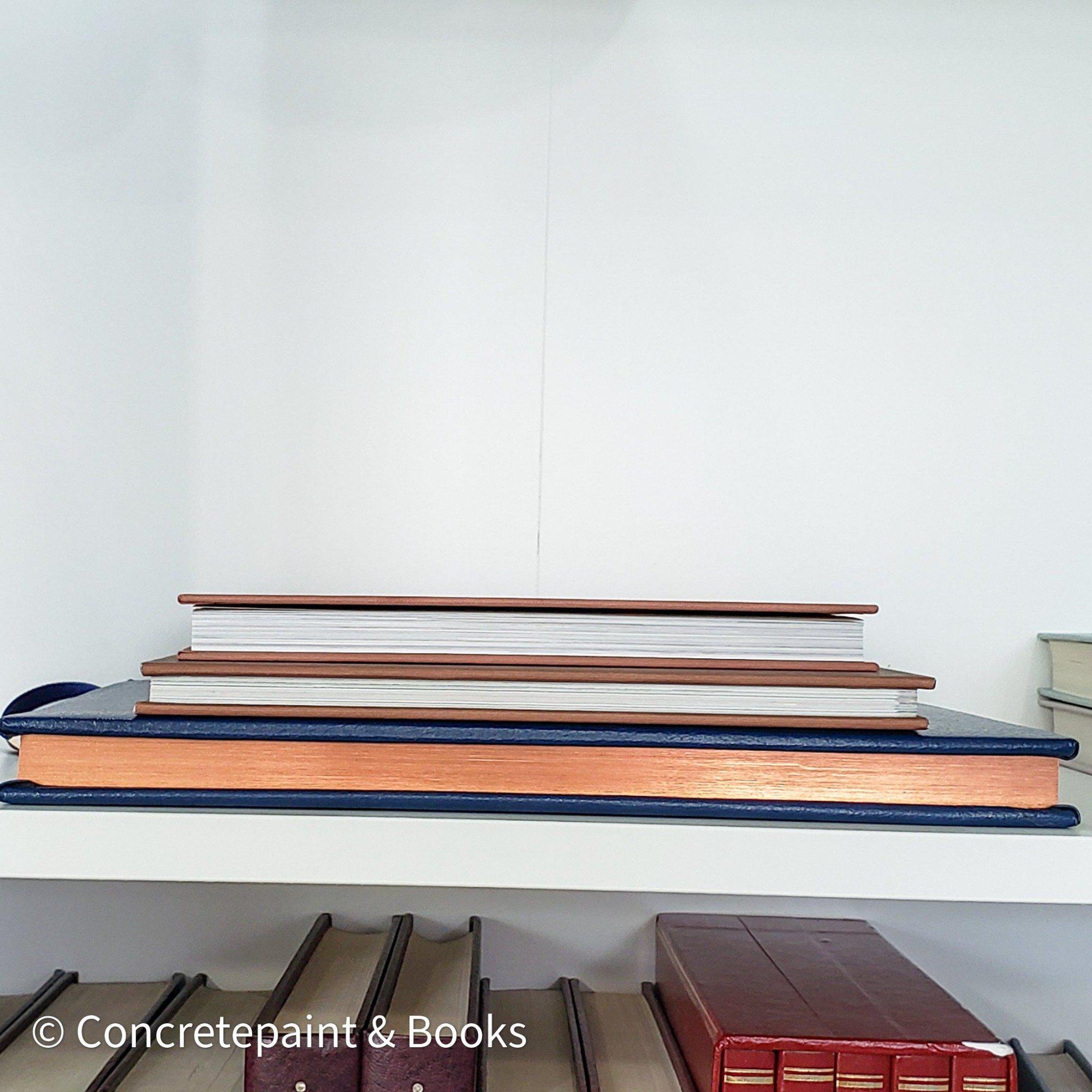 Stack of hardcover books in navy blue and neutral colors. Real books staged and used for decorating.