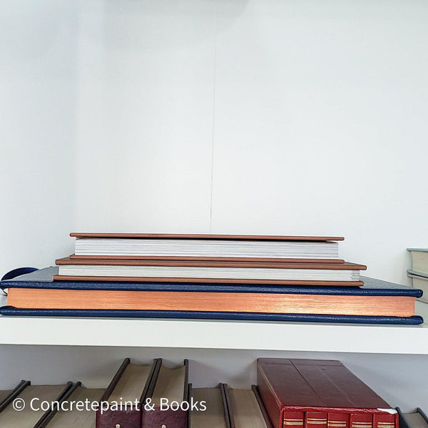 Stack of hardcover books in navy blue and neutral colors. Real books staged and used for decorating.