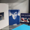 Stack of white and blue hardcover coffee table books. 