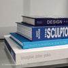 Stack of white and blue hardcover coffee table books. 