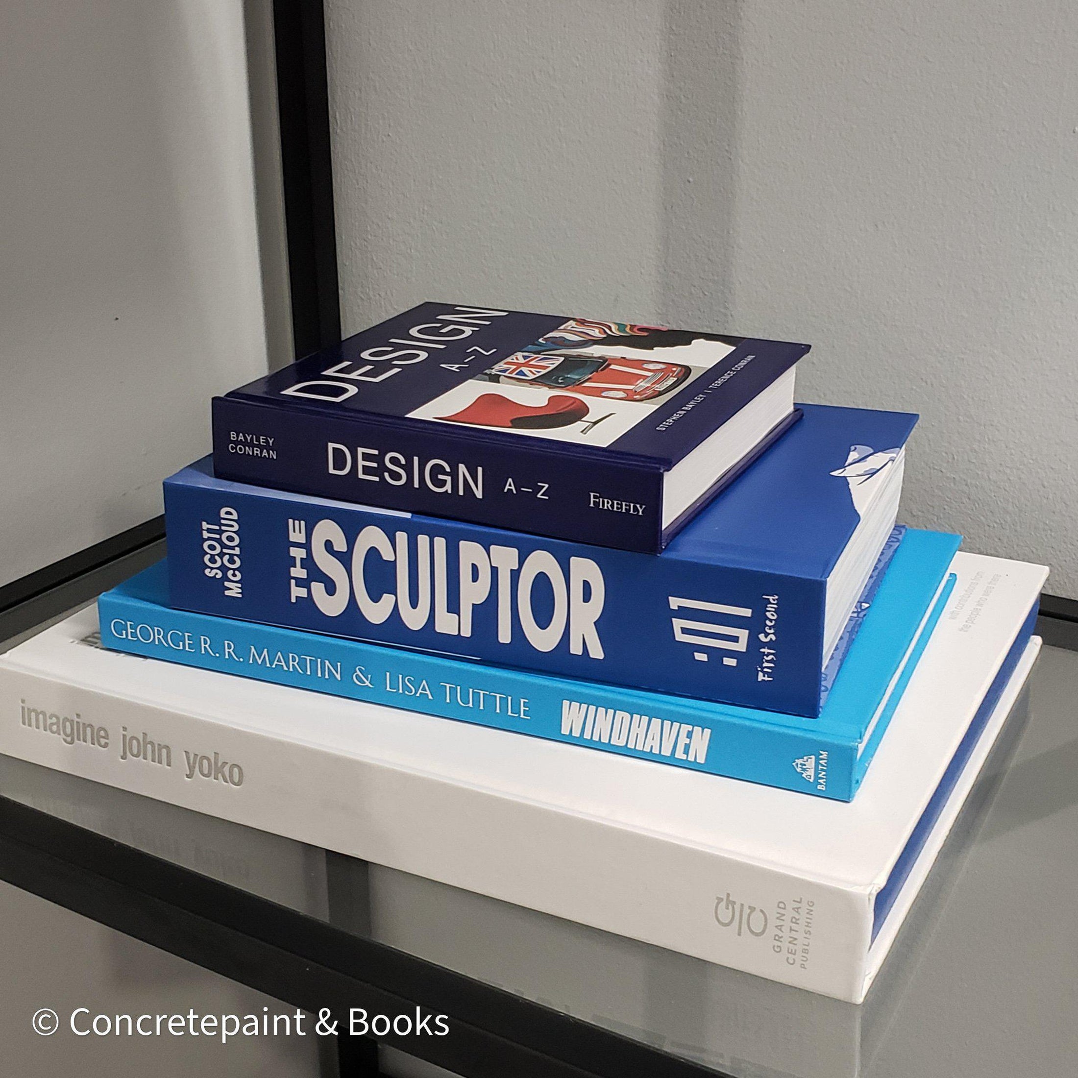 Stack of white and blue hardcover coffee table books. 
